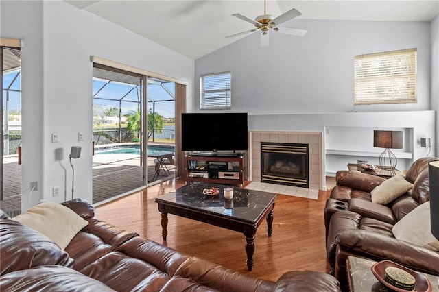 living room with plenty of natural light, ceiling fan, light wood-type flooring, and vaulted ceiling