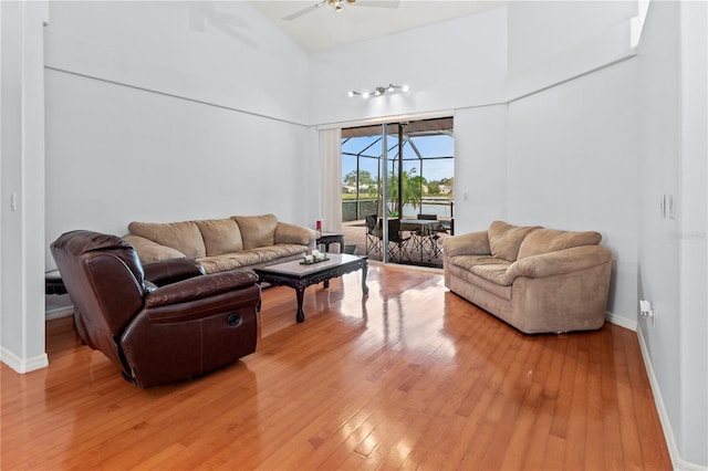 living room with ceiling fan, a towering ceiling, and hardwood / wood-style flooring