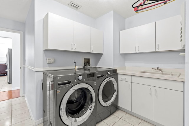 laundry room with cabinets, independent washer and dryer, sink, and light tile patterned floors