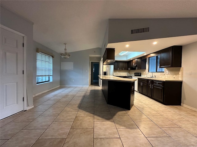 kitchen featuring lofted ceiling, tasteful backsplash, a center island, light tile patterned floors, and stainless steel appliances