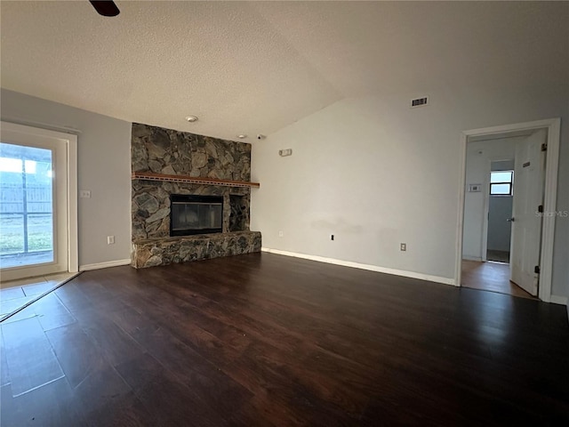 unfurnished living room featuring dark hardwood / wood-style floors, lofted ceiling, a fireplace, and a textured ceiling