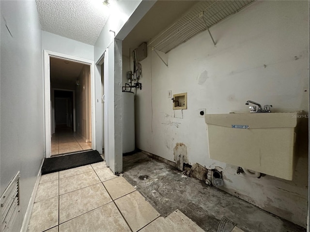 interior space featuring sink, gas water heater, a textured ceiling, hookup for a washing machine, and hookup for an electric dryer