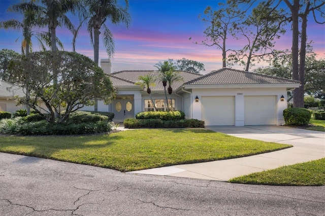 mediterranean / spanish-style home featuring a lawn and a garage