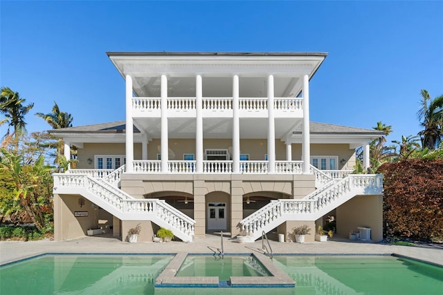 back of house with a swimming pool with hot tub and a patio