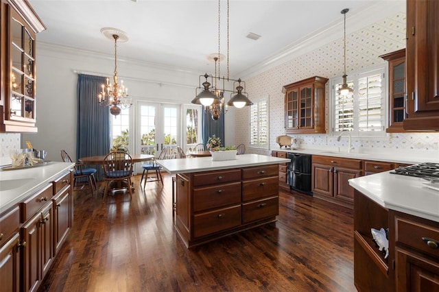 kitchen with dark wood-type flooring, sink, decorative light fixtures, a kitchen island, and a chandelier