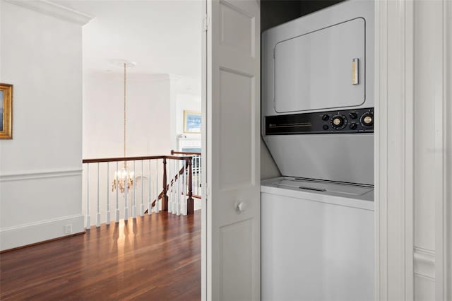 laundry area featuring crown molding, stacked washer / drying machine, and hardwood / wood-style flooring