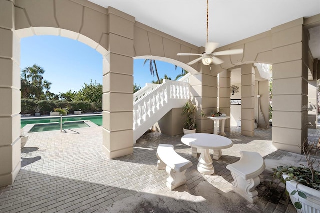 view of patio / terrace with ceiling fan and a pool