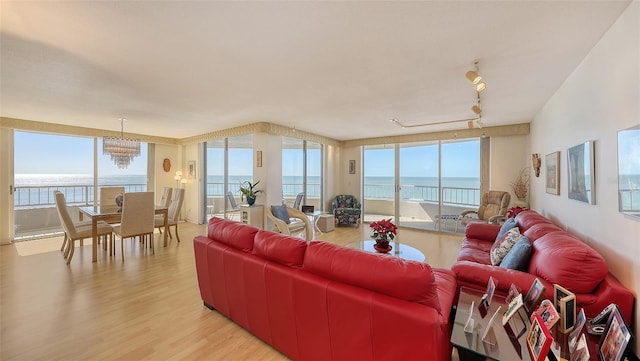 living room with a chandelier, plenty of natural light, a water view, and light hardwood / wood-style floors