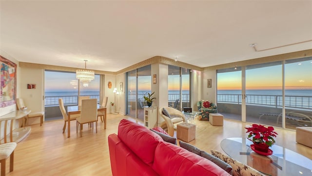 living room with hardwood / wood-style floors, a water view, and an inviting chandelier