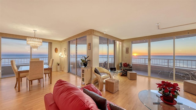 living room featuring hardwood / wood-style floors, a notable chandelier, a water view, and a beach view