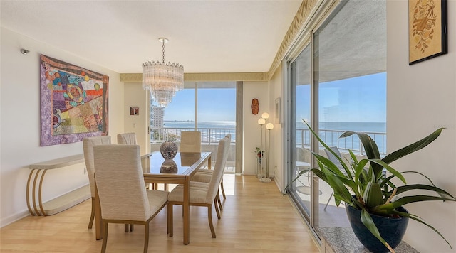 dining space with light hardwood / wood-style floors, a water view, and an inviting chandelier