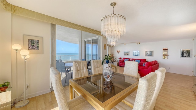 dining area featuring wood-type flooring, a water view, and a notable chandelier