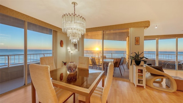 dining space with a chandelier, wood-type flooring, and a water view