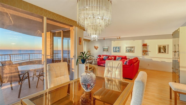 dining room featuring a water view, wood-type flooring, and an inviting chandelier