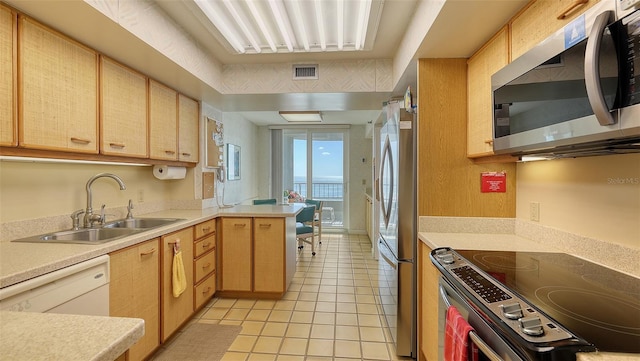 kitchen featuring light brown cabinets, sink, light tile patterned floors, appliances with stainless steel finishes, and kitchen peninsula