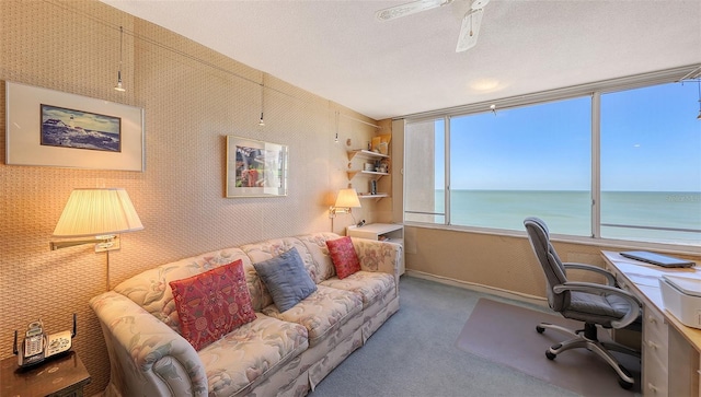 office space featuring carpet flooring, ceiling fan, a water view, and a textured ceiling