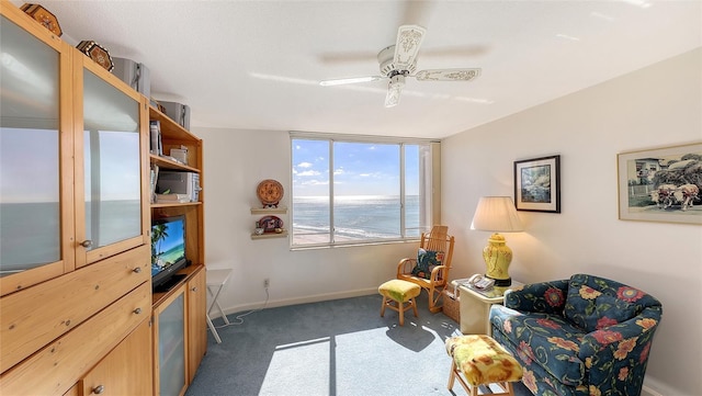 living area with ceiling fan and dark carpet