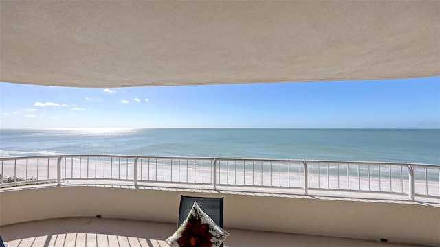 balcony featuring a view of the beach and a water view