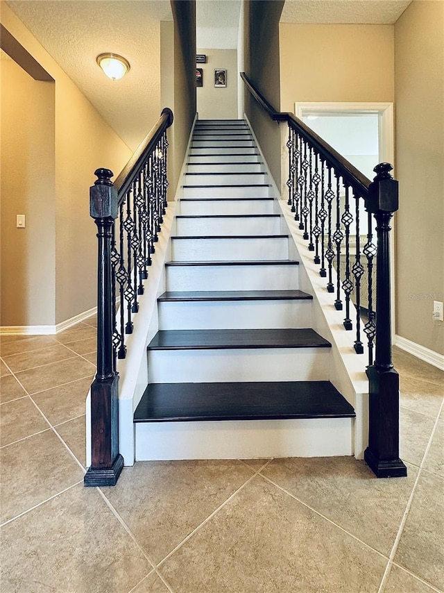 stairway featuring tile patterned flooring and a textured ceiling