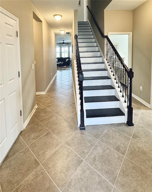 staircase featuring tile patterned flooring, a textured ceiling, and ceiling fan