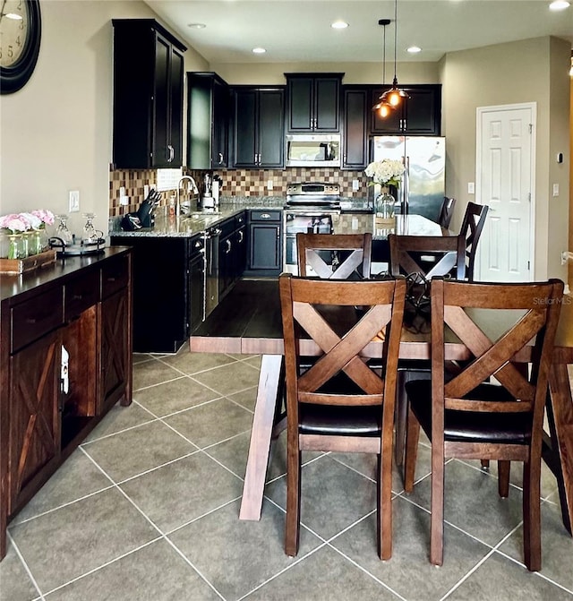 kitchen with pendant lighting, backsplash, sink, tile patterned flooring, and appliances with stainless steel finishes