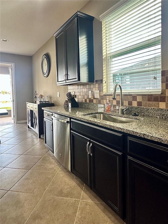 kitchen featuring stainless steel dishwasher, backsplash, light stone countertops, and sink