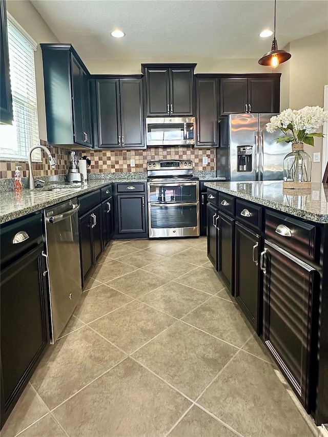 kitchen featuring decorative backsplash, pendant lighting, stainless steel appliances, and light stone counters