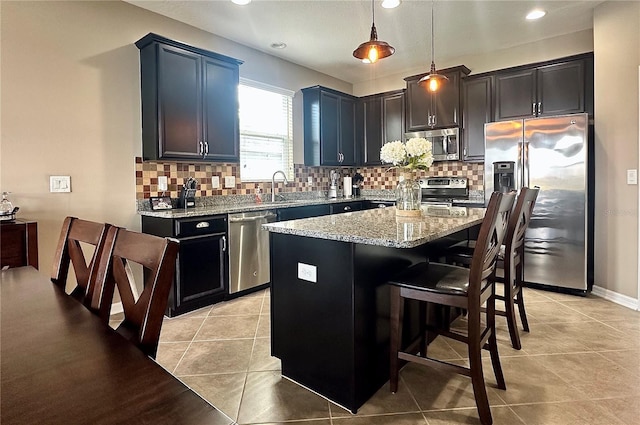 kitchen featuring a center island, light tile patterned floors, stainless steel appliances, and decorative light fixtures