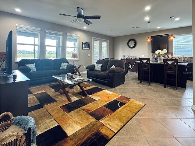 tiled living room featuring ceiling fan and sink