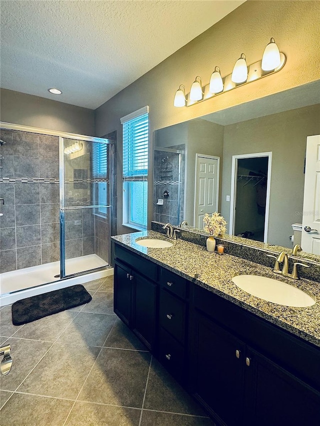 bathroom with tile patterned floors, vanity, a shower with shower door, and a textured ceiling