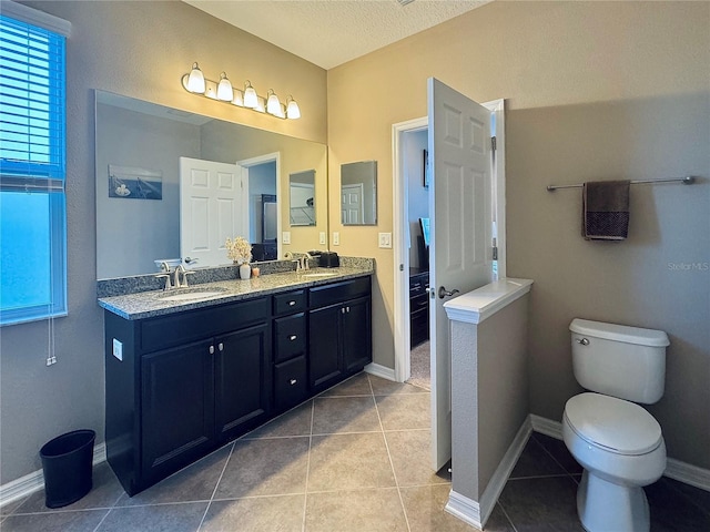 bathroom featuring vanity, a textured ceiling, toilet, and tile patterned flooring