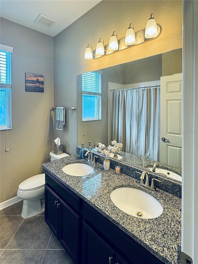 bathroom with tile patterned floors, vanity, toilet, and a healthy amount of sunlight