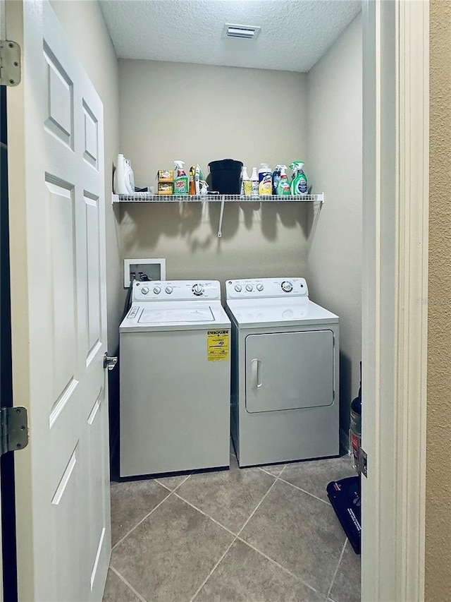 laundry room featuring a textured ceiling, washing machine and dryer, and tile patterned floors