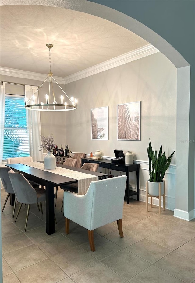 tiled dining room with ornamental molding and a chandelier