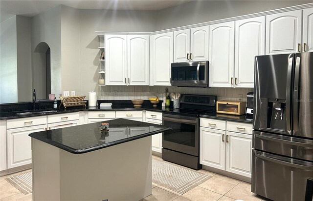 kitchen with sink, stainless steel appliances, light tile patterned floors, and white cabinetry