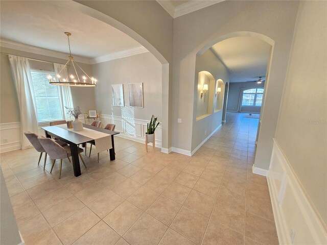 dining area featuring ceiling fan with notable chandelier, light tile patterned flooring, and crown molding