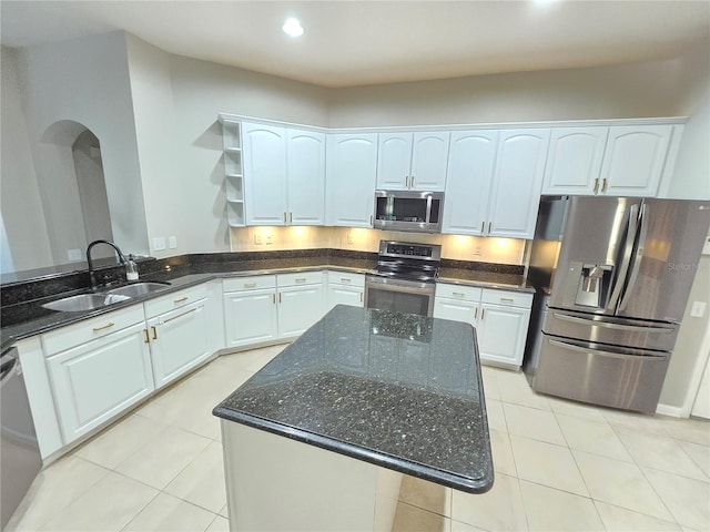 kitchen featuring stainless steel appliances, white cabinetry, sink, and dark stone counters