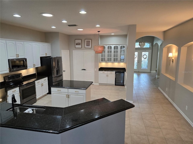 kitchen featuring beverage cooler, stainless steel range with electric stovetop, a kitchen island, white cabinets, and sink