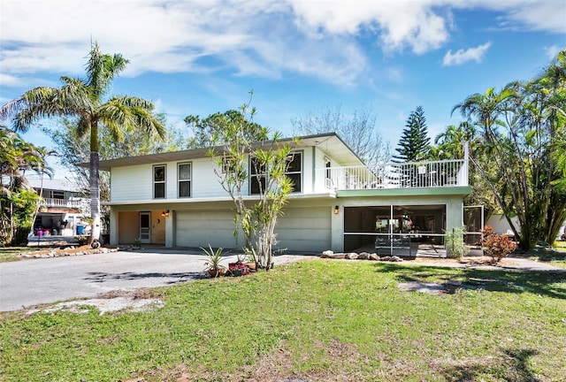 view of front of house featuring a sunroom, a garage, a balcony, and a front yard