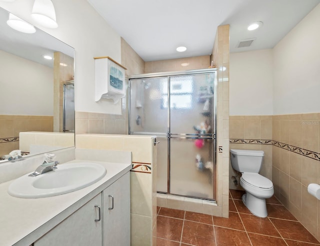 bathroom with tile patterned flooring, toilet, and tile walls