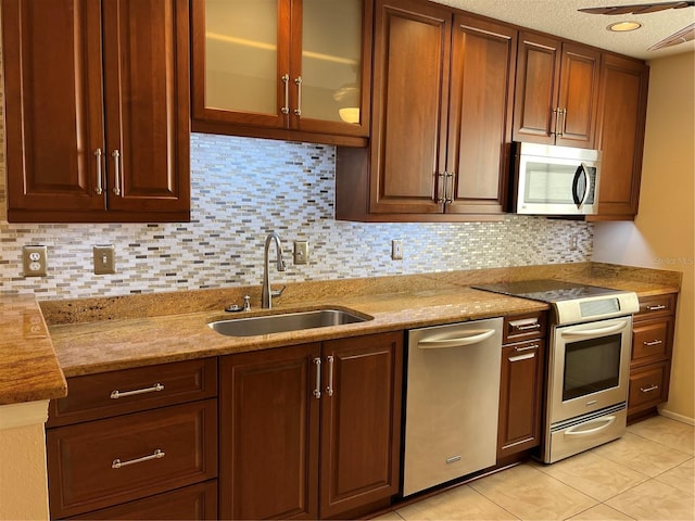 kitchen featuring sink, light stone countertops, appliances with stainless steel finishes, tasteful backsplash, and light tile patterned flooring