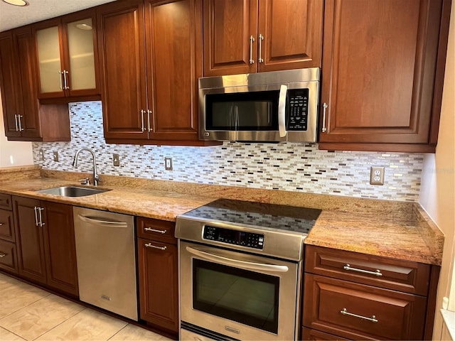 kitchen featuring decorative backsplash, light tile patterned floors, stainless steel appliances, and sink