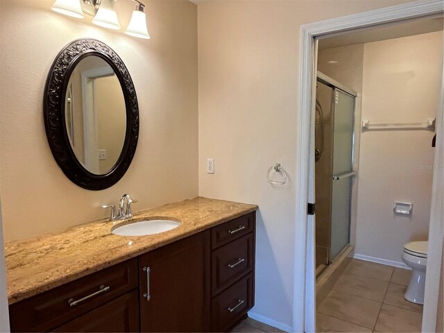 bathroom with tile patterned flooring, vanity, toilet, and walk in shower