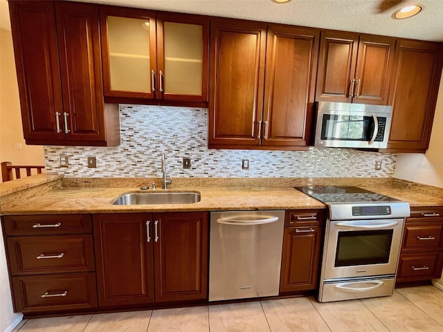 kitchen featuring tasteful backsplash, light stone countertops, sink, and stainless steel appliances