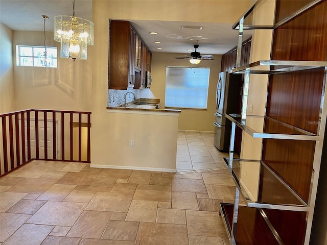 kitchen with sink, stainless steel appliances, backsplash, decorative light fixtures, and ceiling fan with notable chandelier