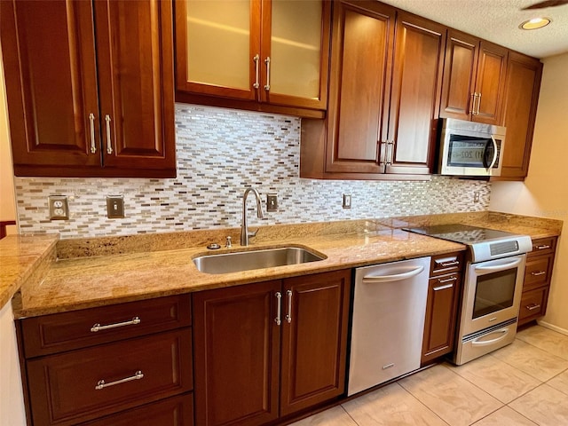 kitchen with decorative backsplash, light stone countertops, sink, and appliances with stainless steel finishes