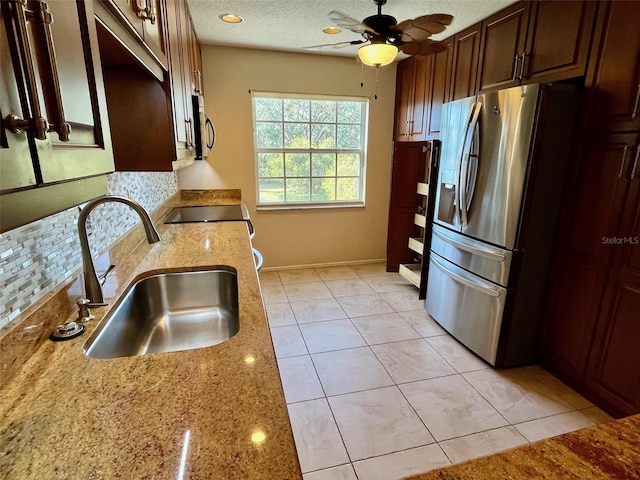 kitchen featuring ceiling fan, sink, light stone counters, light tile patterned floors, and appliances with stainless steel finishes