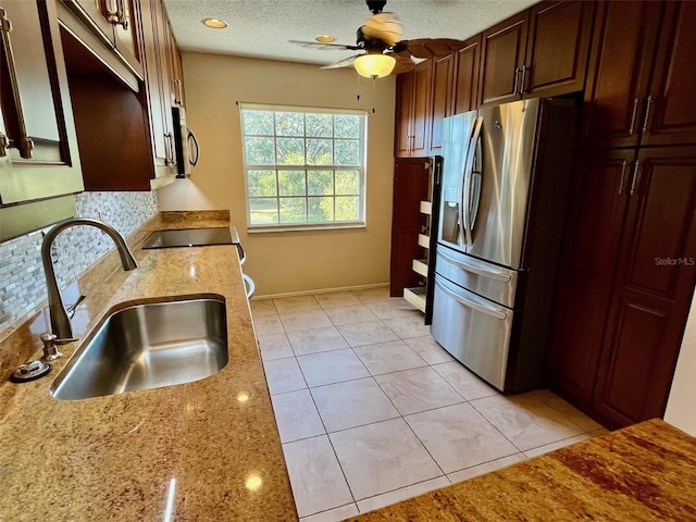 kitchen featuring stainless steel fridge, sink, light tile patterned floors, and light stone counters