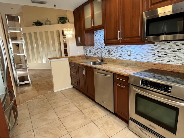 kitchen featuring sink, pendant lighting, stainless steel appliances, light stone countertops, and backsplash