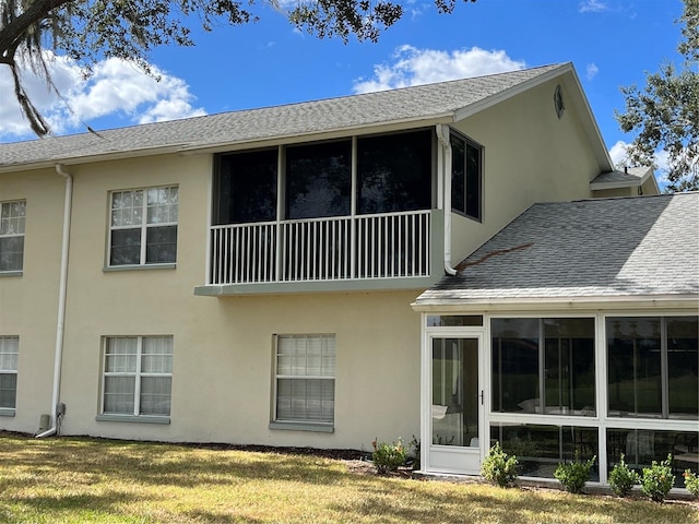 back of property featuring a sunroom and a lawn